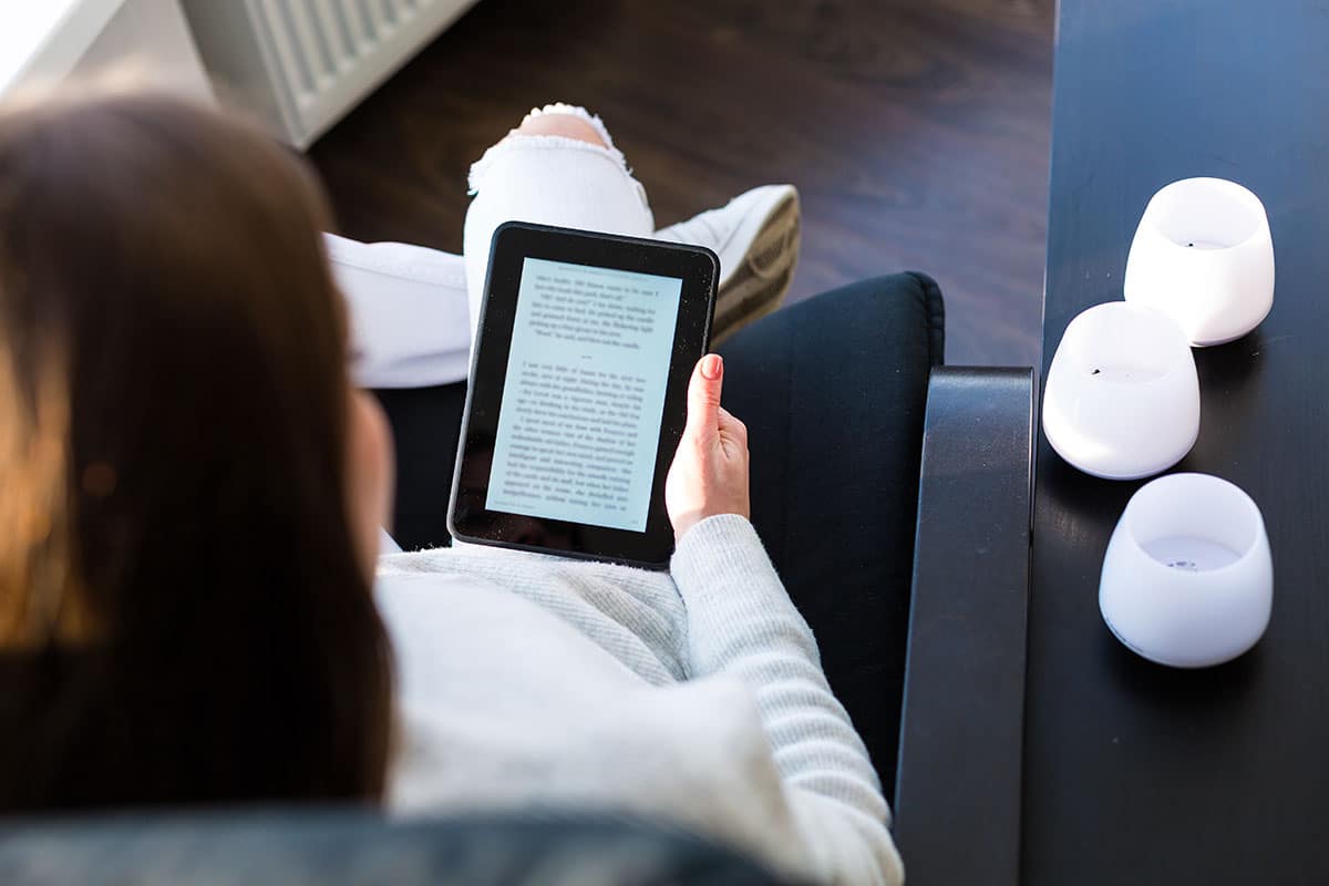 Woman sitting by the window with an e book